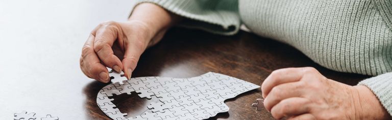 Älterer Mensch legt ein Puzzle in der Form eines menschlichen Kopfes