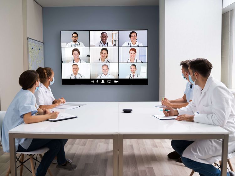 Ärzteteam bespricht sich in der Gruppe mit Online-Teilnehmern