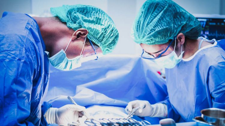 Eine Ärztin und ein Arzt mit Mundschutz sortieren chirurgische Instrumente vor einer Operation