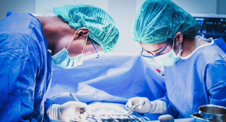 Eine Ärztin und ein Arzt mit Mundschutz sortieren chirurgische Instrumente vor einer Operation