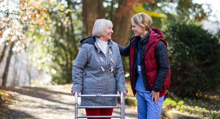 Pflegerin geht mit Senioren draußen im Herbst spazieren