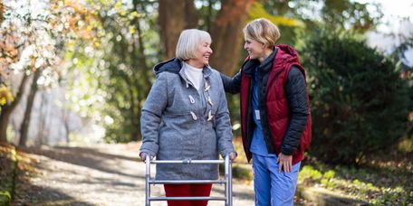 Pflegerin geht mit Senioren draußen im Herbst spazieren