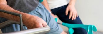 Therapeutin unterstützt orthopädischen Patienten beim Treppensteigen