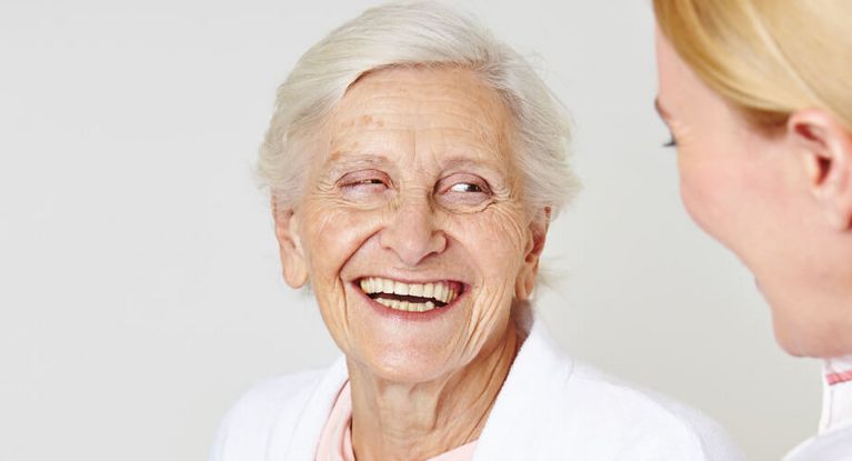 Seniorin lacht weiblicher Pflegekraft an