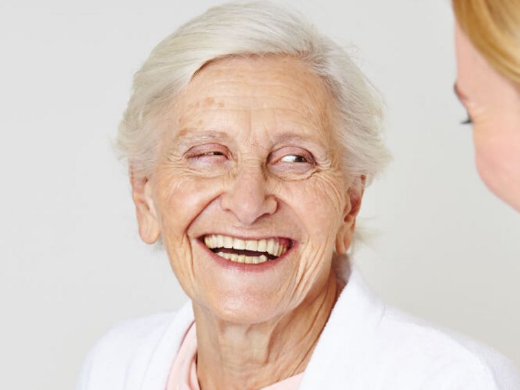 Seniorin lacht weiblicher Pflegekraft an