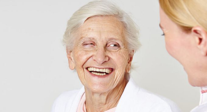 Seniorin lacht weiblicher Pflegekraft an