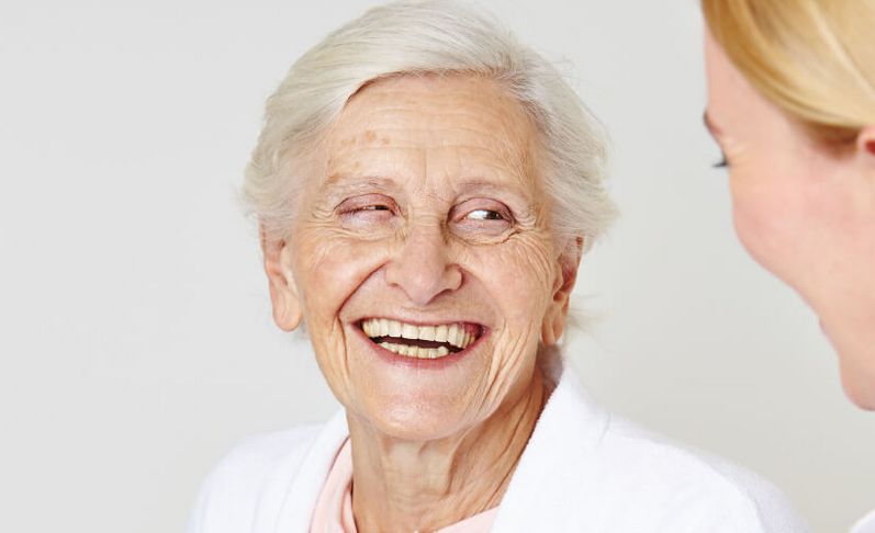 Seniorin lacht weiblicher Pflegekraft an