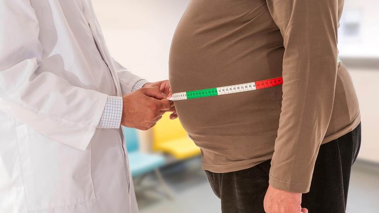 Arzt untersucht Bauchumfang eines übergewichtigen Patienten