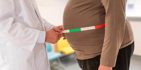 Arzt untersucht Bauchumfang eines übergewichtigen Patienten