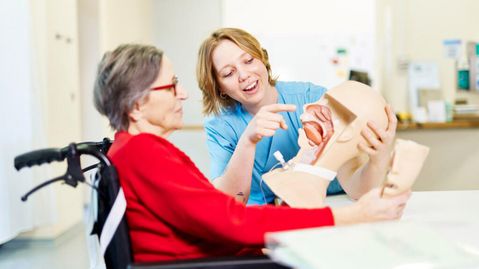 Therapeutin erklärt einer älteren Patientin mithilfe eines anatomischen Modells den Schluckvorgang im Rahmen der Schlucktherapie