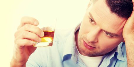 Männliche Person mit einem Glas Alkohol