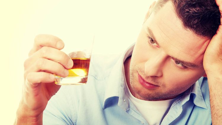 Männliche Person mit einem Glas Alkohol