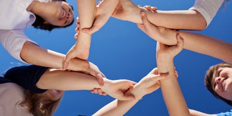 Partnerschaftliche_Zusammenarbeit_von_Anfang_an Vier Menschen verbinden Ihrer Hände zu einem Kreis