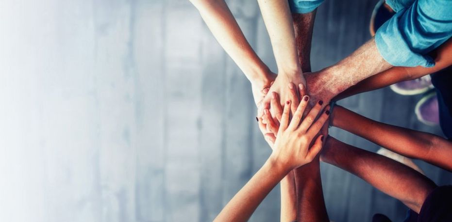 Viele Hände unterschiedlicher Hautfarbe liegen übereinander