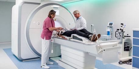 Arzt und Pflegekraft bereiten einen Patienten für die Untersuchung im MRT vor.