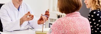 Ein Herzchirurg erklärt Patienten und Angehörigen den Eingriff an einem Herzmodell