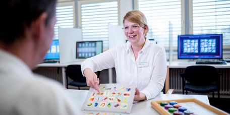 Therapeutin zeigt Patient bunte Bilder beim Gedächtnistraining. 