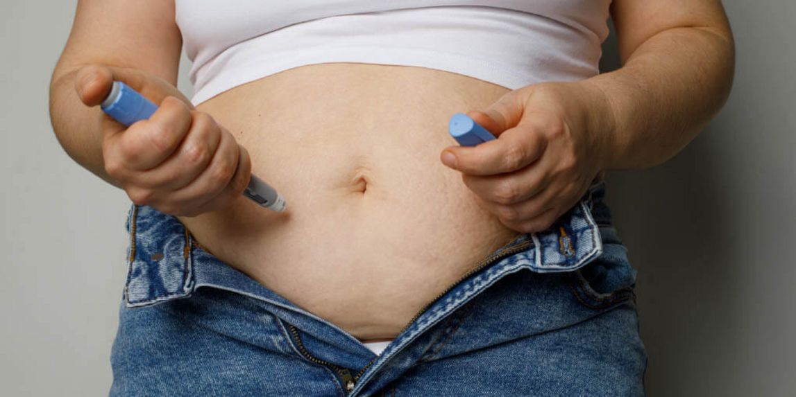 Übergewichtige Patientin spritzt sich mit einem Pen in den Bauch