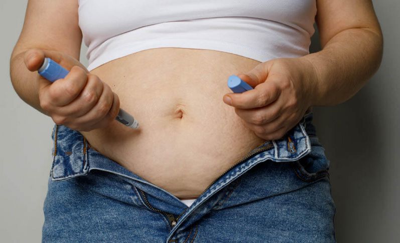 Übergewichtige Patientin spritzt sich mit einem Pen in den Bauch