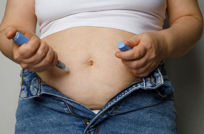 Übergewichtige Patientin spritzt sich mit einem Pen in den Bauch