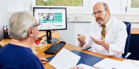 Patientenbesprechung Arzt klärt Patientin über kardiologische Reha auf