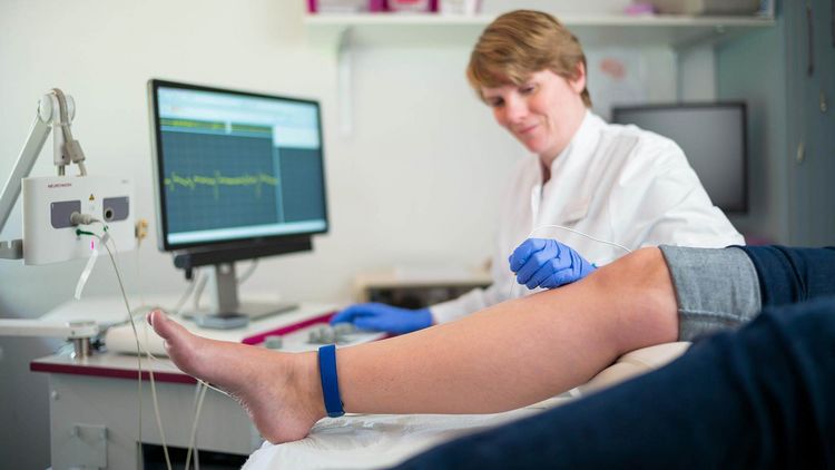Ärztin untersucht Bein eines Patienten mit Polyneuropathie