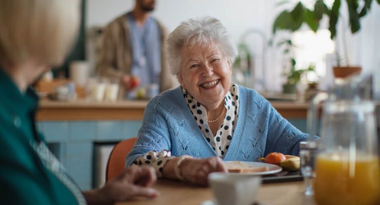 Ältere Frau freut sich beim Frühstück