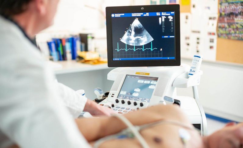 Arzt führt bei einem Patienten eine Herzuntersuchung per Ultraschall durch. 
