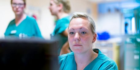 Pflegekräfte besprechen Schichtübergabe und schauen auf den Bildschirm