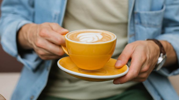Nahaufnahme eines Manns, der eine Kaffeetasse in der Hand hält