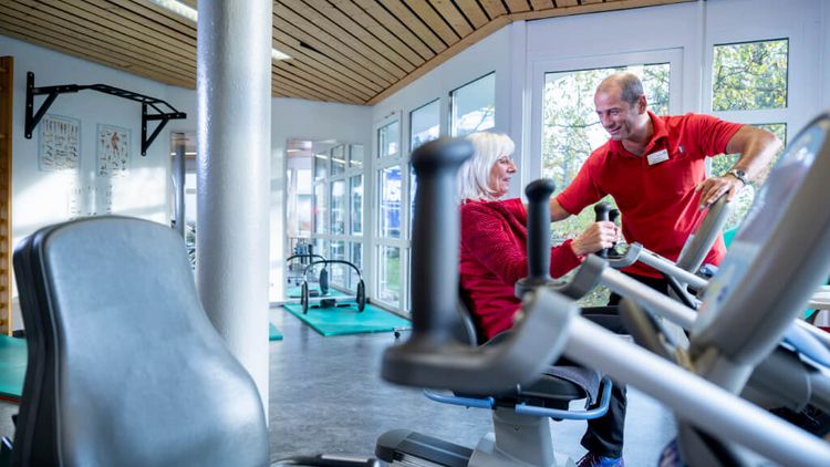Ein Therapeut weist eine Patientin beim Kardiotraining am Gerät ein
