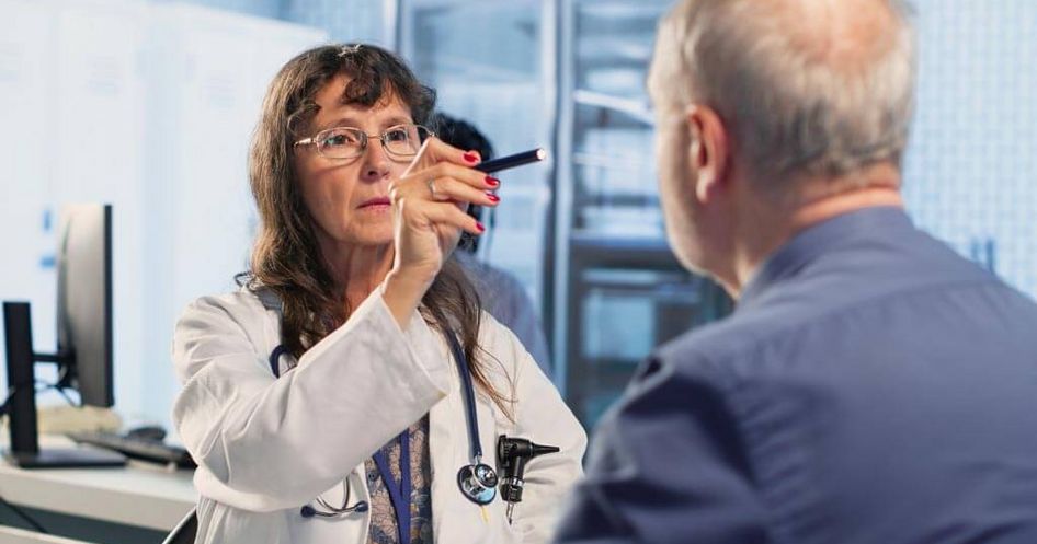 Ärztin untersucht mit einer Leuchte die Augen eines Patienten, neurologische Untersuchung, Diagnostik