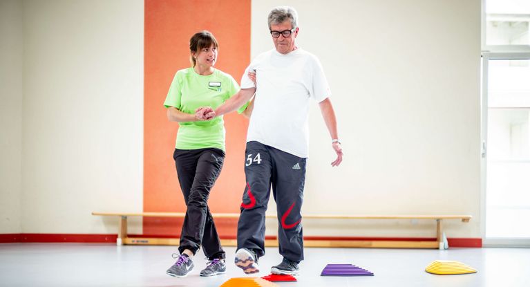 Therapeutin unterstützt Patient beim Gleichgewichtstraining