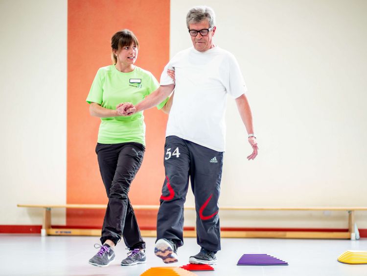 Therapeutin unterstützt Patient beim Gleichgewichtstraining