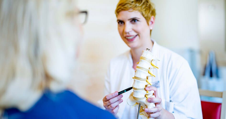 Ärztin erklärt Patientin die Wirbelsäule