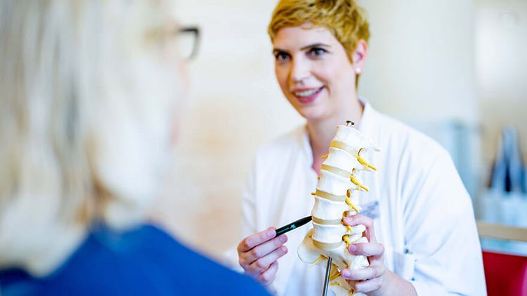 Ärztin erklärt Patientin die Wirbelsäule