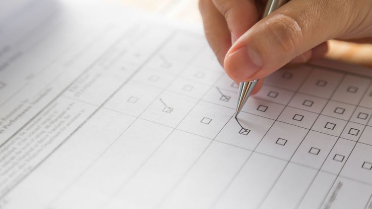 Hand füllt Checkboxen mit einem Kugelschreiber aus