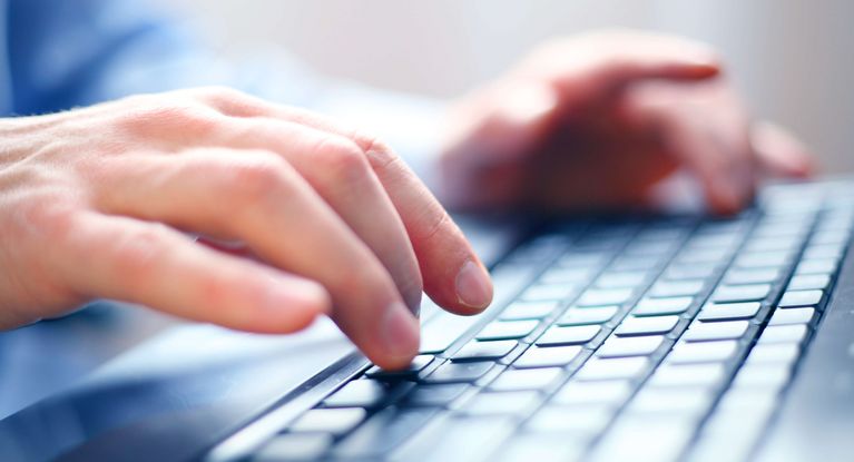 Zwei Hände schreiben auf einer Computertastatur