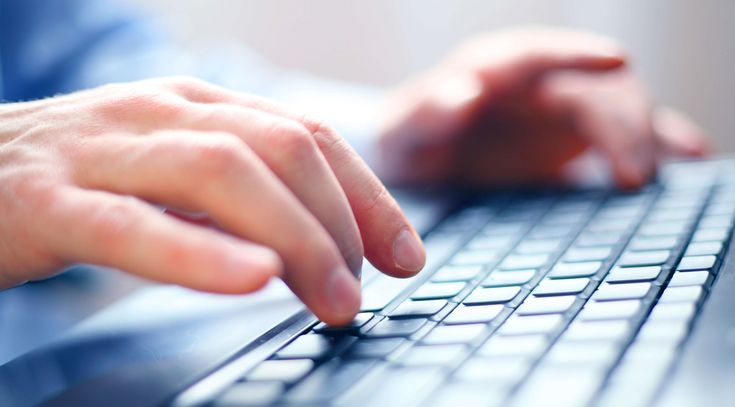Zwei Hände schreiben auf einer Computertastatur