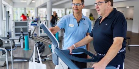 Patient auf dem Laufband, Therapeut leitet an