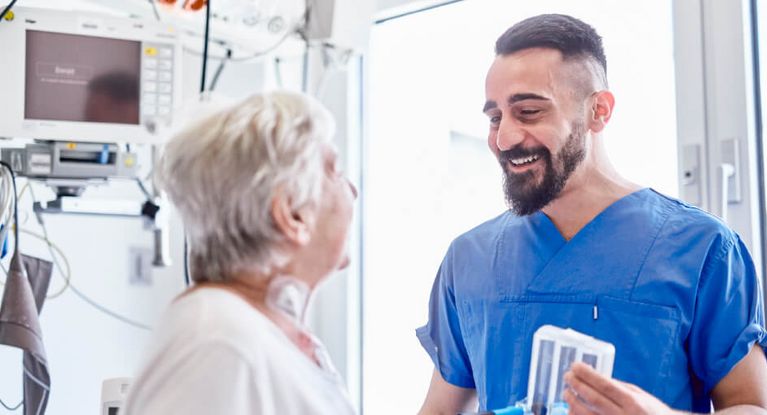 Lächende Pflegekraft im Akuthaus spricht mit Patientin