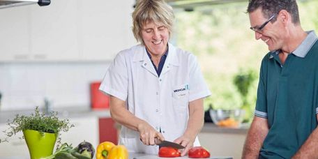 Therapeutin und Patient schneiden Gemüse