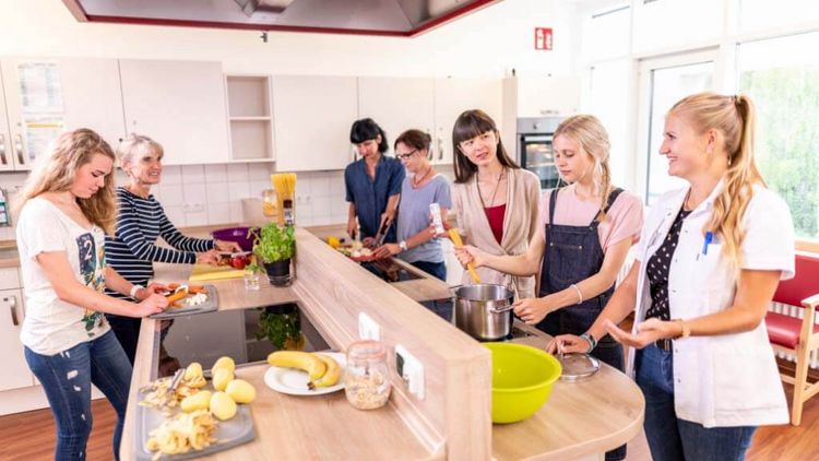 Patientinnen mit Therapeutin in der Lehrküche einer Rehaklinik bei der Ernährungstherapie