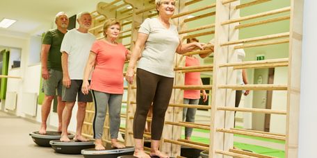 Ihre_Physiotherapie-Patientinnen_in_guten_Haenden Ältere Patienten trainieren in einer Physiotherapiepraxis an einer Sprossenwand