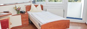 Bett und Tisch im Zimmer in der MEDICLIN Staufeburg Klinik in Durbach