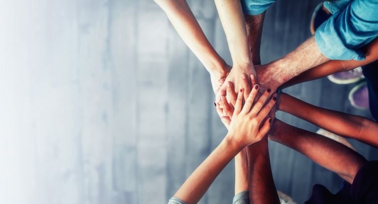 Menschen legen ihre Hände in Teamarbeit übereinander