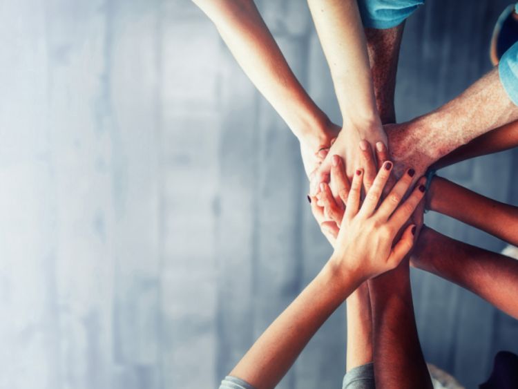 Menschen legen ihre Hände in Teamarbeit übereinander