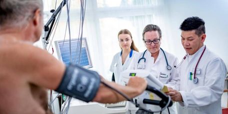 Patient beim Belastungs-EKG, Ärzte und Pflegekraft stehen dabei