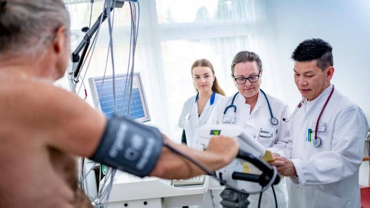 Patient beim Belastungs-EKG, Ärzte und Pflegekraft stehen dabei
