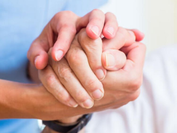 Pflegerin hält die Hand eines älteren Patienten